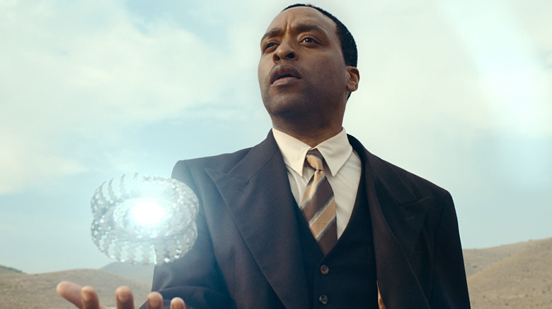 Faraday holding a glowing widget in The Man Who Fell to Earth