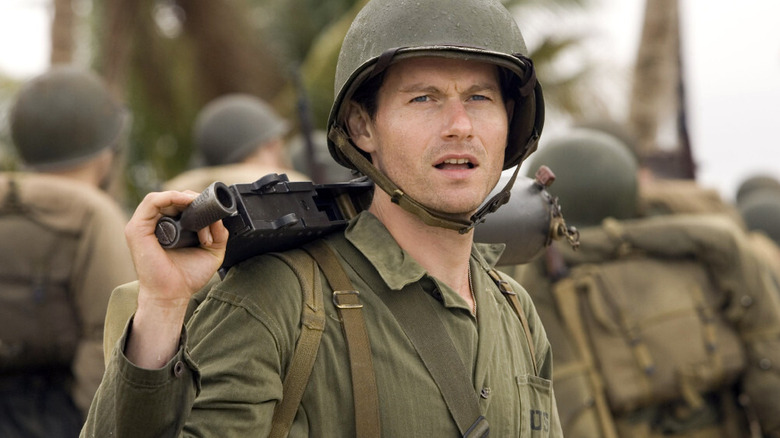 Robert Leckie holding a machine gun over his shoulder in The Pacific