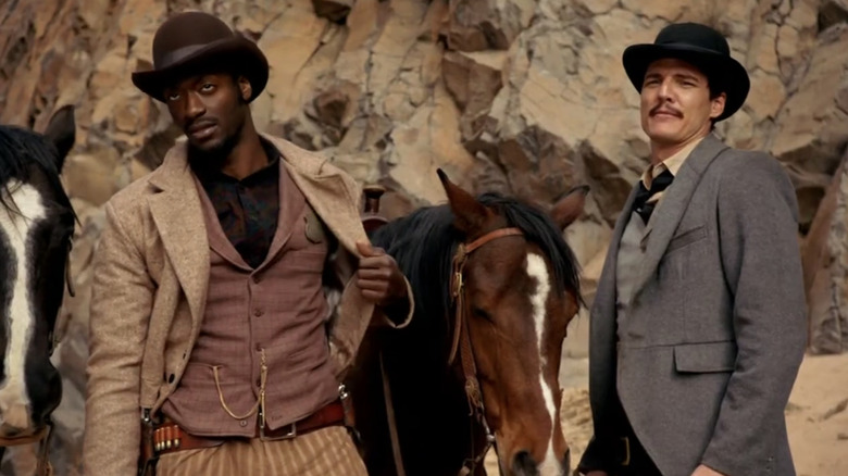 Aldis Hodge's Agent Mercer and Pedro Pascal's Agent Ortega stand next to their horses in The Sixth Gun