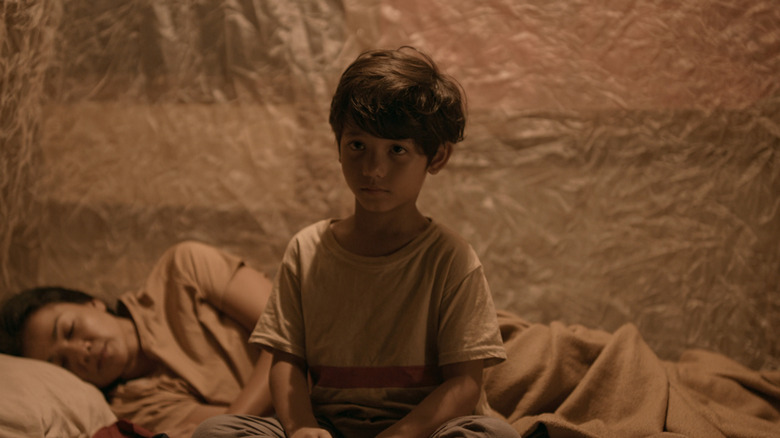 Faqih Alaydru's Syafin sits on a bed as Nirina Zubir's Ipah sleeps in Joko Anwar's Nightmares and Daydreams
