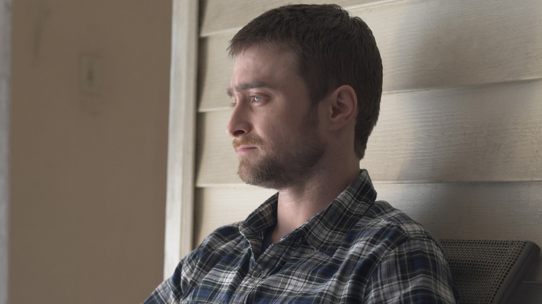 Sean sitting in front of a house looking sad in Beast of Burden