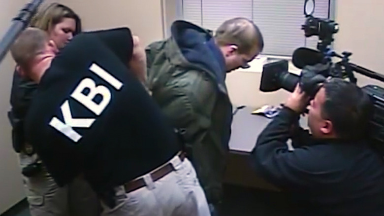 A man being arrested in Predators, with a documentary camera crew filming his face