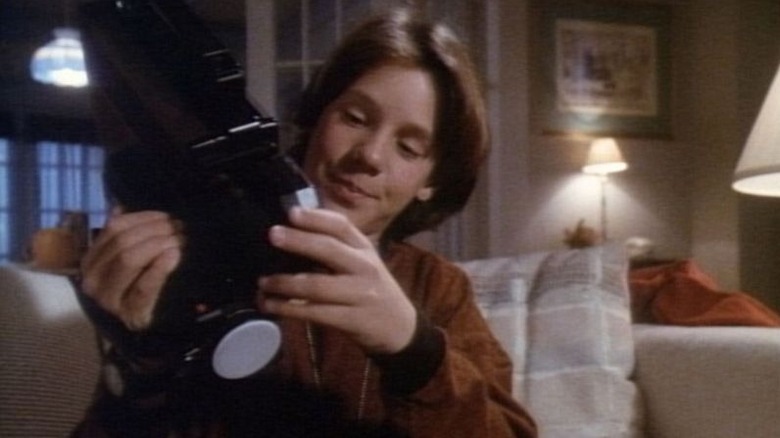 Omri Katz as Marshall Teller holding a movie camera in Eerie, Indiana