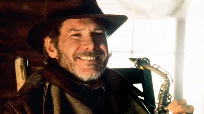 Harrison Ford's Indiana Jones grinning and holding a saxophone on The Young Indiana Jones Chronicles