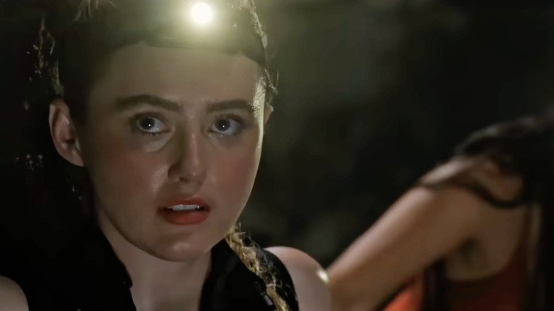 Kathryn Newton as Sara McKenna wearing a headlight in a cave in The Devil's Mouth