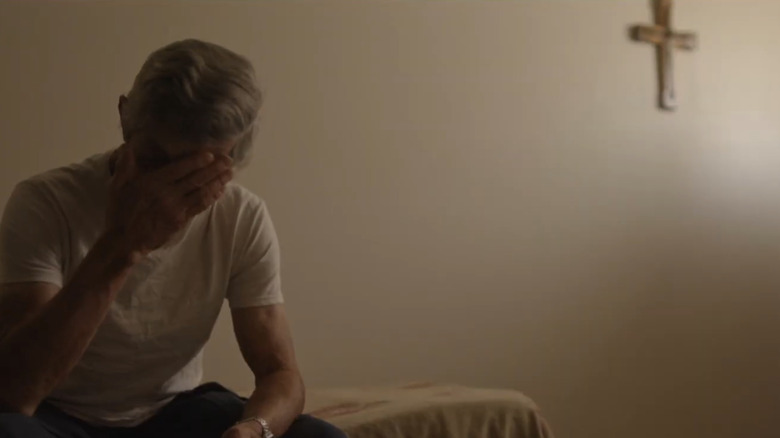 A man puts his head in his hand in a bare room in Murder in the Bayou