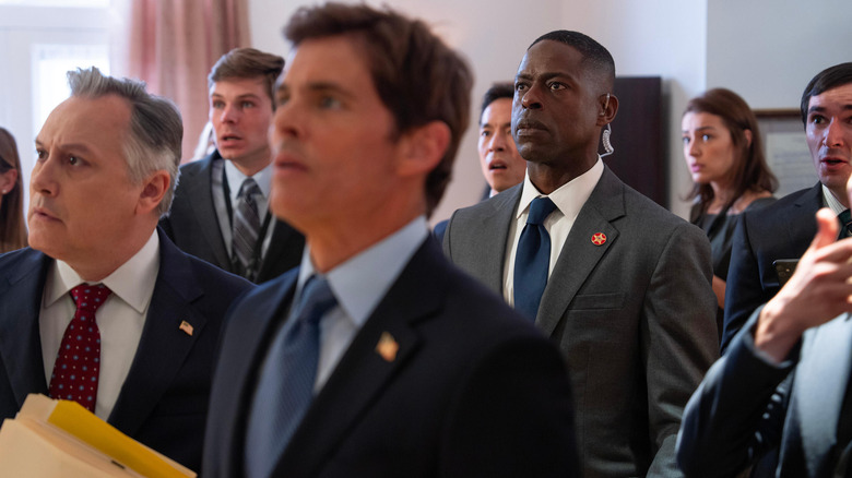 Cal and Xavier watch a television instructor surrounded by people concerned in paradise
