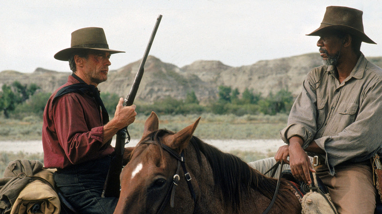 Clint Eastwood's Will Munny on horseback with a rifle talking to his partner Ned Logan, played by Morgan Freeman