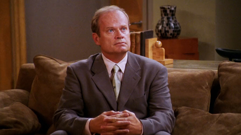 Kelsey Grammer as Frasier Crane sits on his couch in his apartment looking up in Frasier
