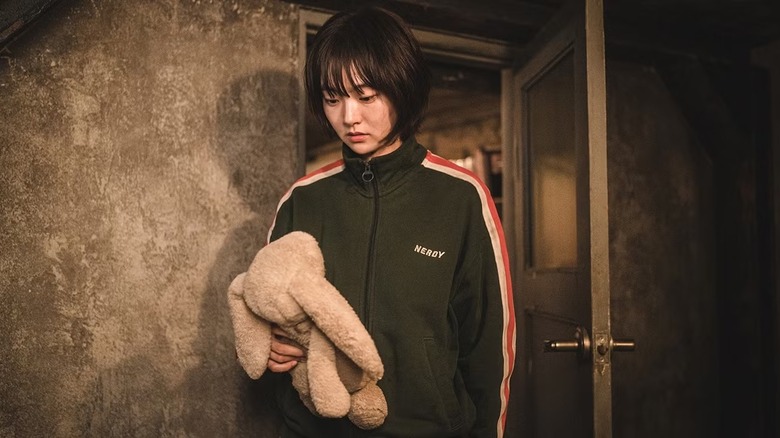 Jeong Ji-an (Kim Hye-jun) contemplatively holds a stuffed rabbit in A Shop for Killers