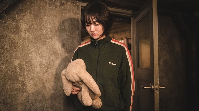 Jeong Ji-an (Kim Hye-jun) contemplatively holds a stuffed rabbit in A Shop for Killers