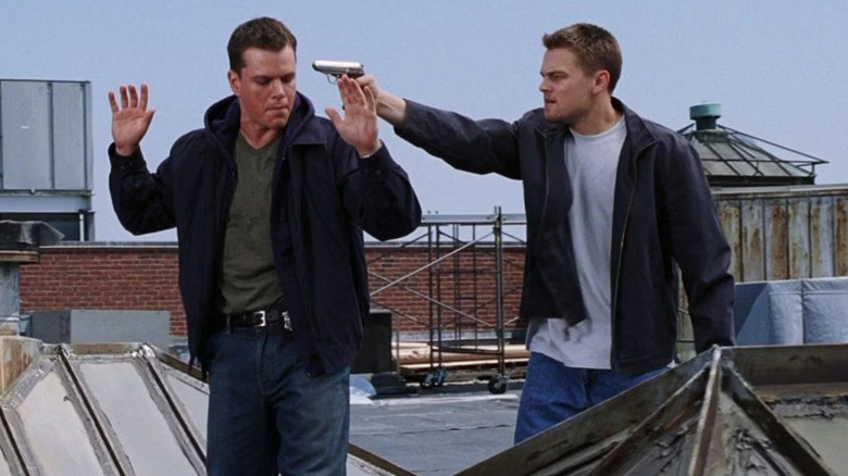 Billy points a gun at Colin on a roof in The Departed