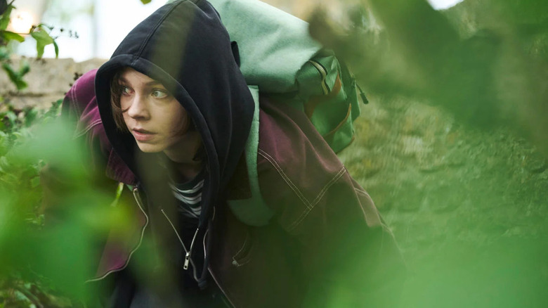 Pip in a hoodie sneaking through the underbrush in A Good Girl's Guide to Murder