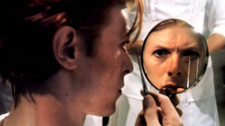 Thomas looks at his human contacts that have fused into his eyes in The Man Who Fell to Earth