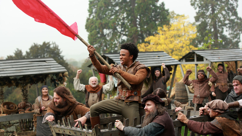 Sid waving a red flag while being paraded around town in Galavant