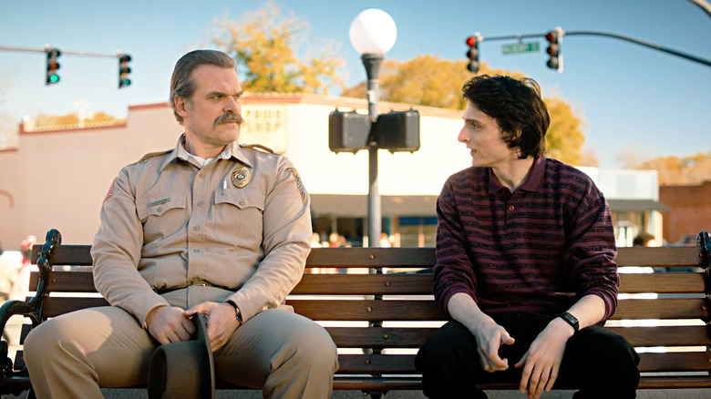 David Harbour's Jim Hopper sits alongside Finn Wolfhard's Mike Wheeler on a bench in Stranger Things.jpg