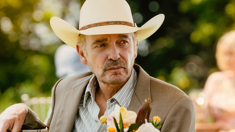 Billy Bob Thornton's Tommy Norris sits at a table outside during a party in Landman
