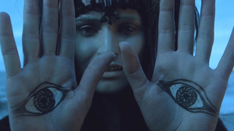 A believer of the new religion on the moon holds up their palm in On the Silver Globe
