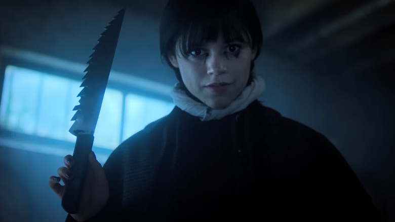 Wednesday Addams holding a knife and looking creepy in Wednesday