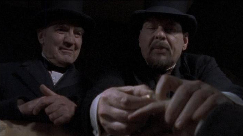 Two men in bowler hats inspecting a corpse in Dead Man's Gun