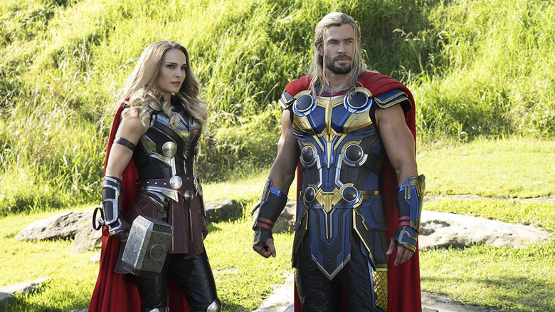 Natalie Portman as Jane Foster standing next to Chris Hemsworth as Thor in a field in Thor: Love and Thunder