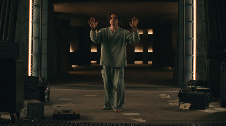 Lewis Pullman as Bob wearing hospital scrubs and holding his hands up in surrender in Thunderbolts