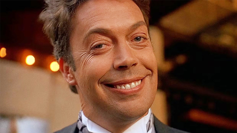 Tim Curry as Mr. Hector smiling broadly and wearing a suit in Home Alone 2: Lost in New York