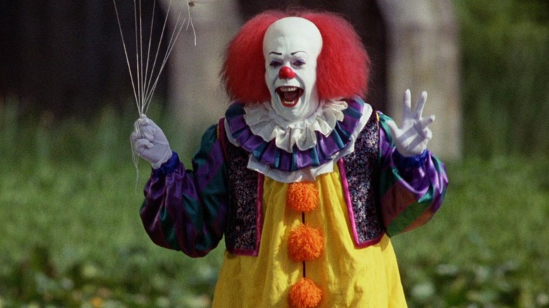 Pennywise cackling and holding balloons in It