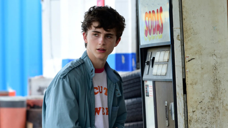 Timothée Chalamet as Daniel standing next to a soda vending machine in Hot Summer Nights