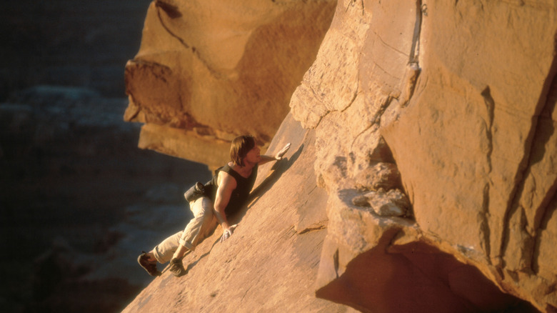 Ethan Hunt, with long hair, rising across a rocky face at the beginning 