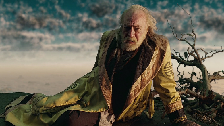 Dr. Parnassus, on the ground in a strange wasteland, wearing a silk robe in The Imaginarium of Dr. Parnassus