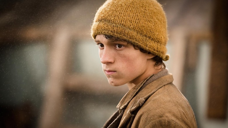 Tom Hiddleston as Thomas Nickerson wearing a yellow cap in In the Heart of the Sea