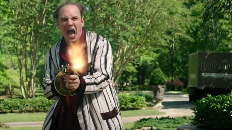 Tom Hardy disparando una ametralladora en una bata de baño como Al Capone en Capone