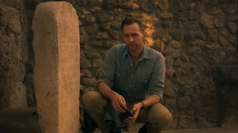 Tom Hiddleston crouched down by a pillar in Pompeii: Out of Time