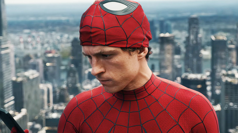 Tom Holland's Peter Parker looks at his phone as he stands high above New York in Spider-Man: Brand New Day