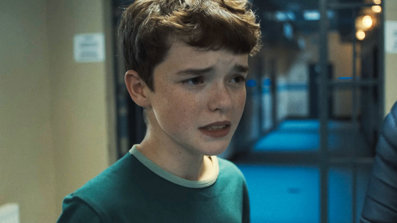 Owen Cooper's Jamie Miller looks concerned as he stands in a police station hallway in Adolescence