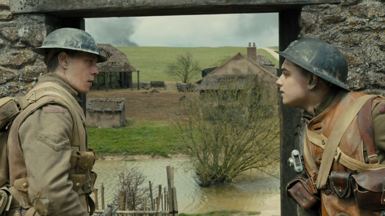 George MacKay's William Schofield and Dean-Charles Chapman's Thomas Blake stand either side of a doorway in the countryside in 1917