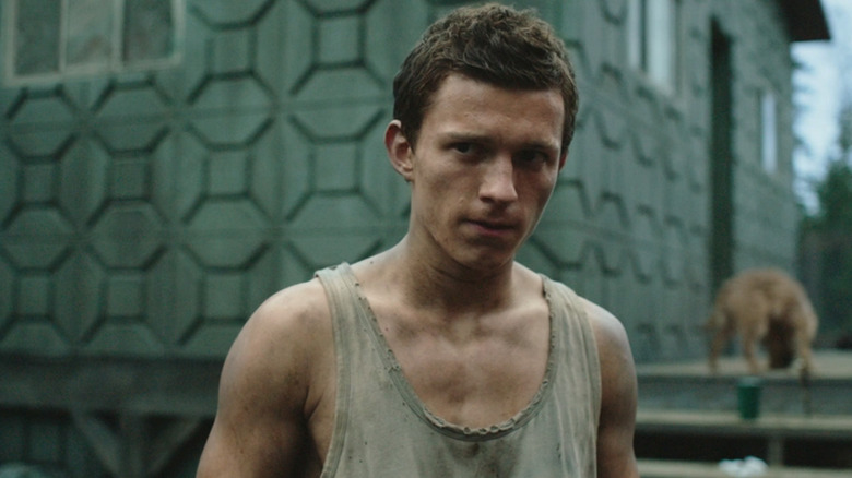 Tom Holland's Todd Hewitt is seen in closeup as he stands outside a house in Chaos Walking