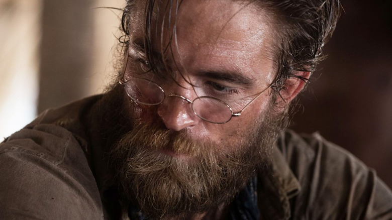 Robert Pattinson as Henry Costin wearing glasses and looking thoughtful in The Lost City of Z