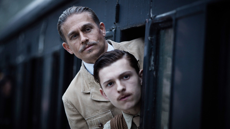 Charlie Hunnam as Percy Fawcett and Tom Holland as Jack Fawcett standing on a train in The Lost City of Z