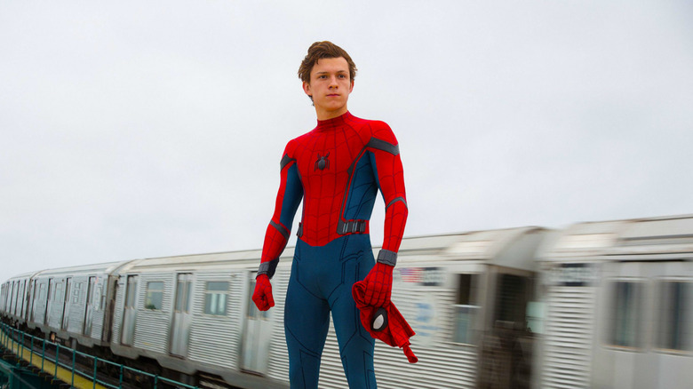Spider-Man, his mask off, standing in front of a moving train in Spider-Man: Homecoming
