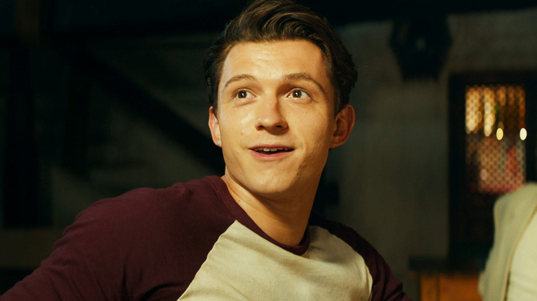 Tom Holland's Nathan Drake smiles as he turns around in his seat in Uncharted