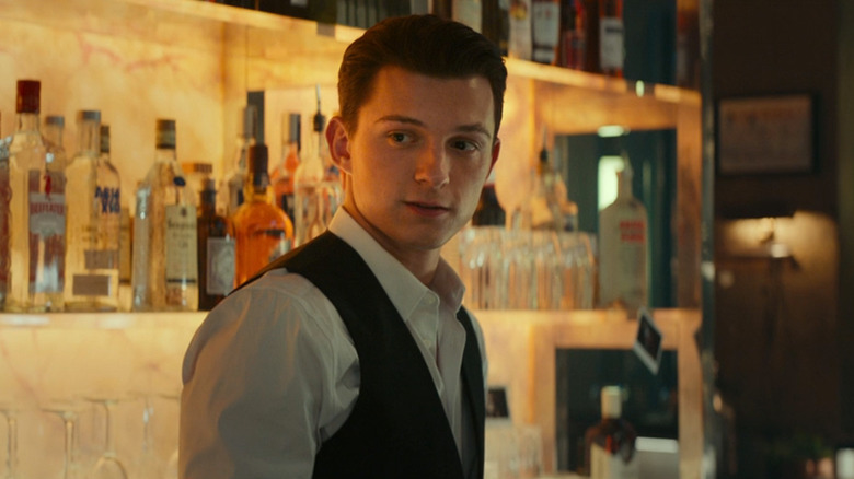 Tom Holland's Nathan Drake stands behind a bar in Uncharted