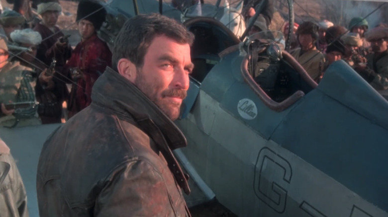 Tom Selleck's Patrick O'Malley looks over his shoulder as he stands by a plane in High Road to China