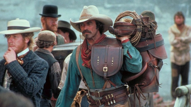 Quigley holding a saddle in Quigley Down Under