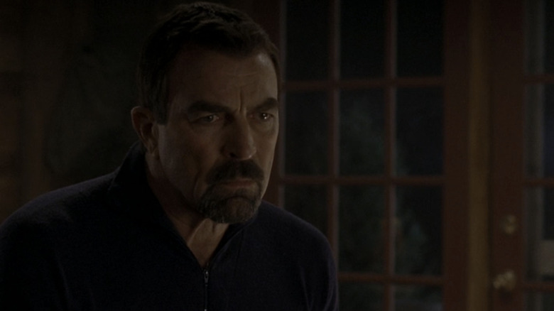 Tom Selleck's Jesse Stone looks off intently as he sits in his living room in Jesse Stone Stone Cold