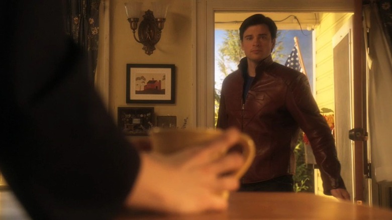 Clark Kent entering a house wearing a red leather jacket with the Superman emblem in Smallville