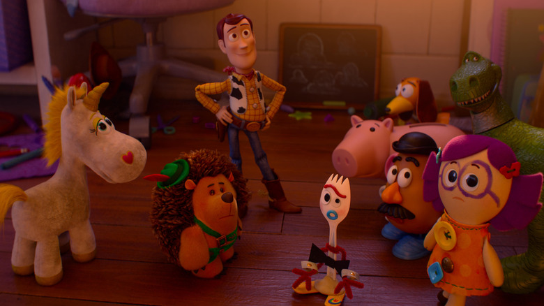 Tom Hanks as the voice of Woody standing on the floor of a children's bedroom with several other toys in Toy Story 5