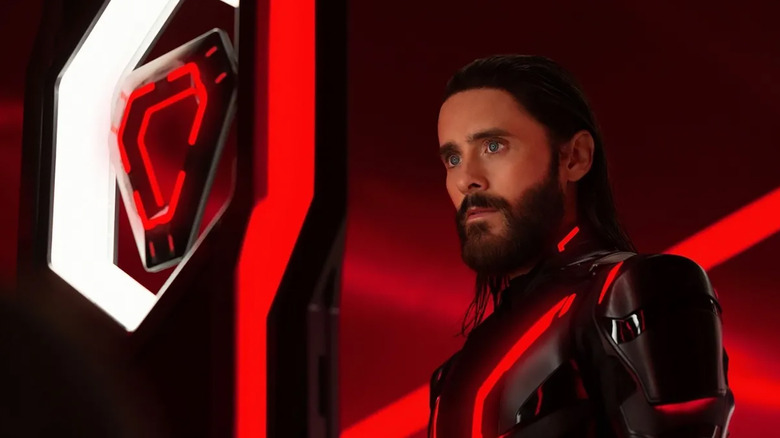 Ares looks at a glowing red orange triangular light disc in a panel that rises out of the floor in Tron: Ares