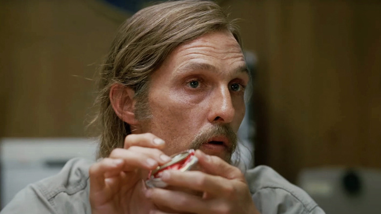 Matthew McConaughey's Rustin Cohle holds a beer can in an interrogation room in True Detective